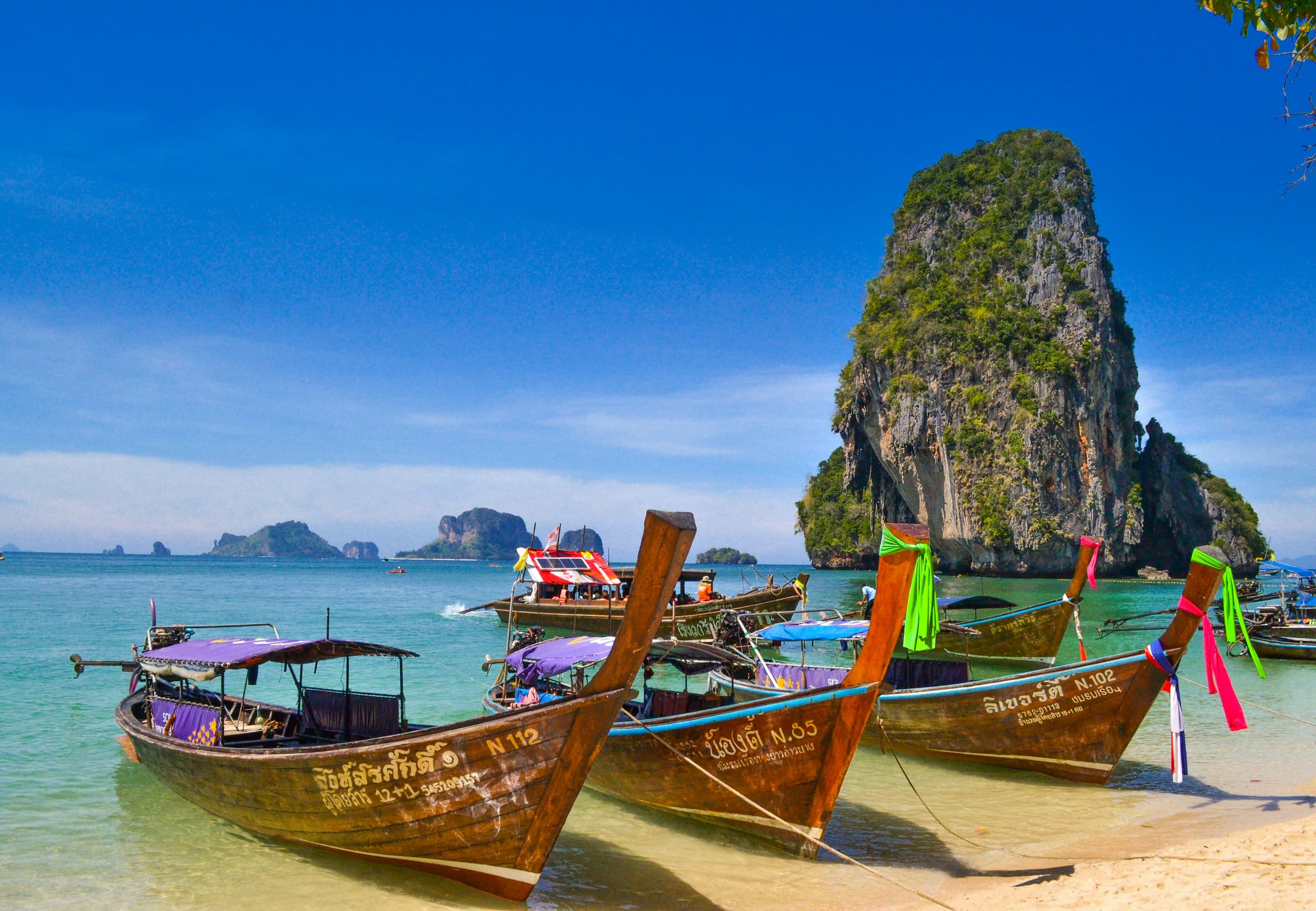 Traditional long-tail boats in turquoise water on a Thailand coast